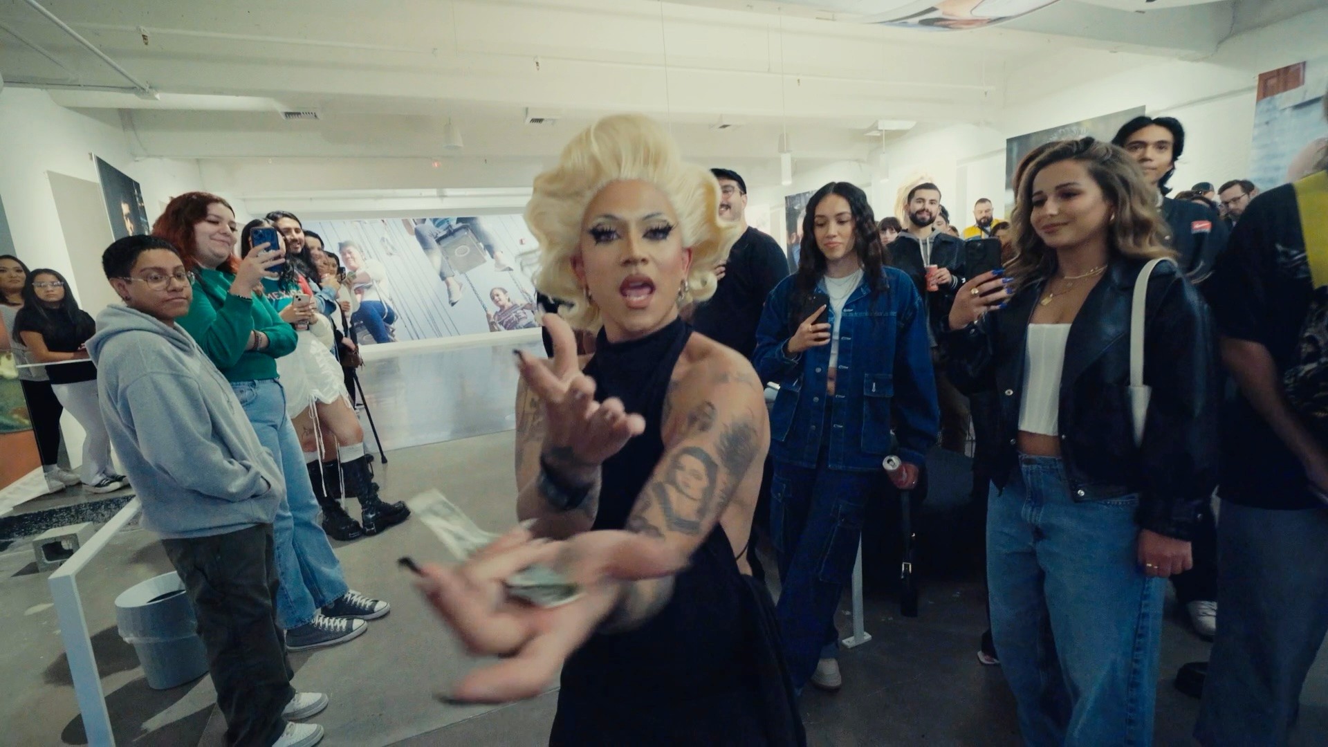 A person with blonde hair holding money in front of a crowd.