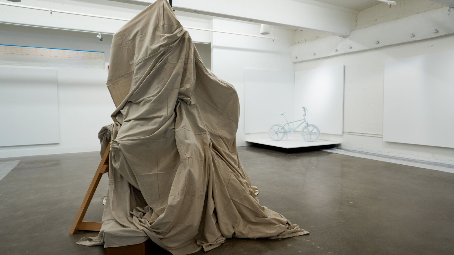Industry One gallery with white walls and drop cloth sculpture in middle of floor