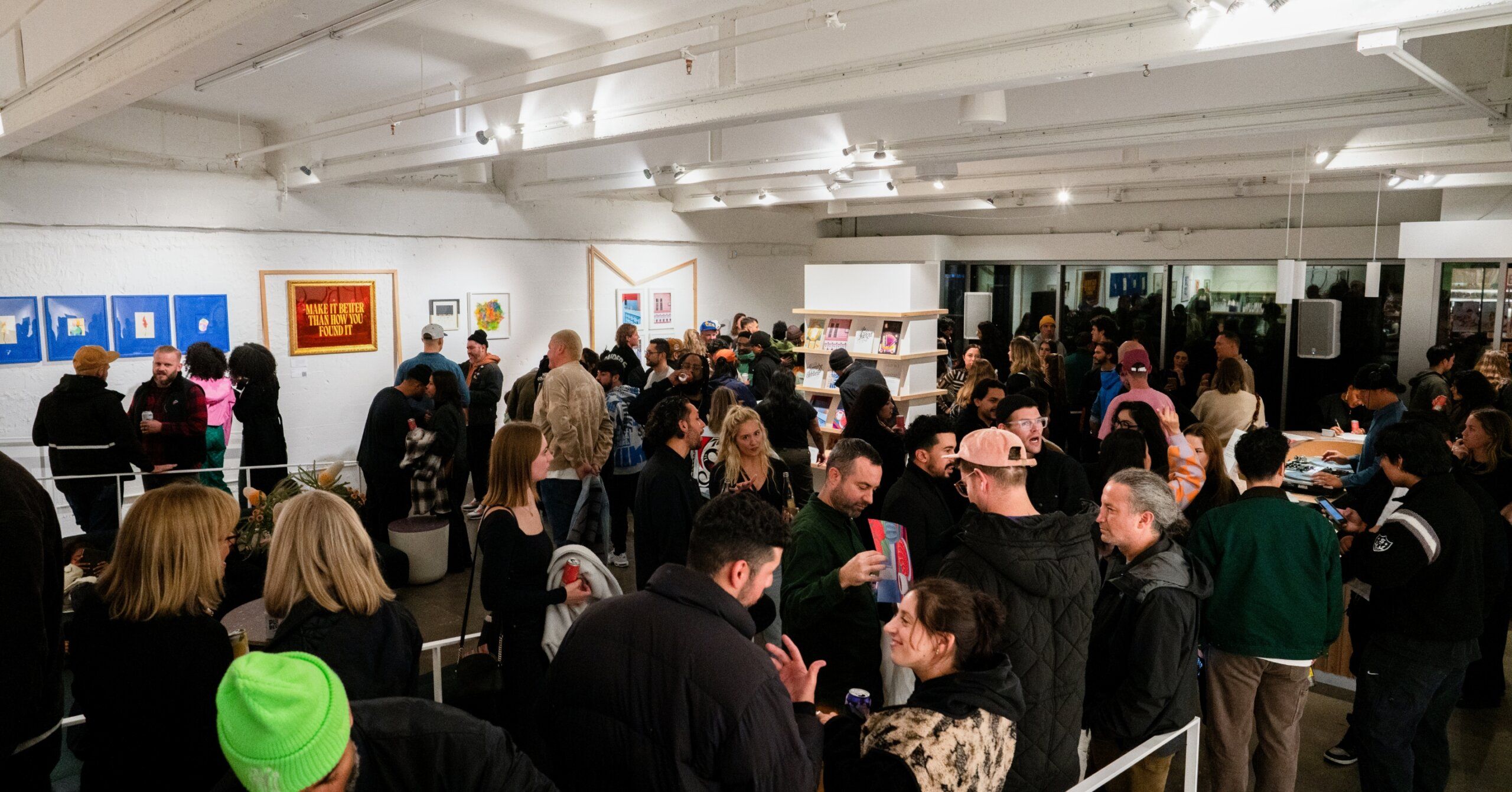 A crowd of people standing in an art gallery opening party.