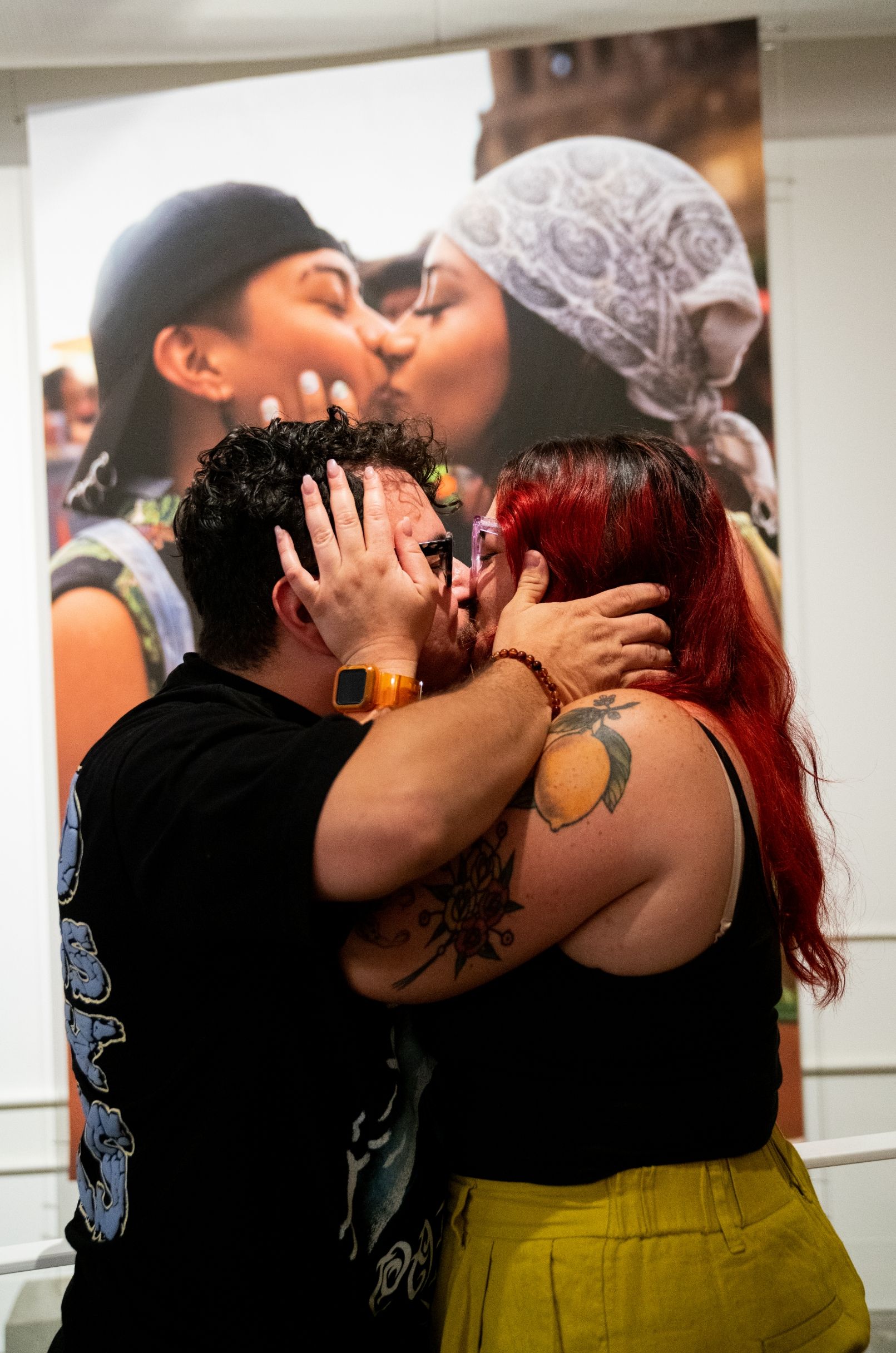 Two people kiss in front of a large print of two people kissing