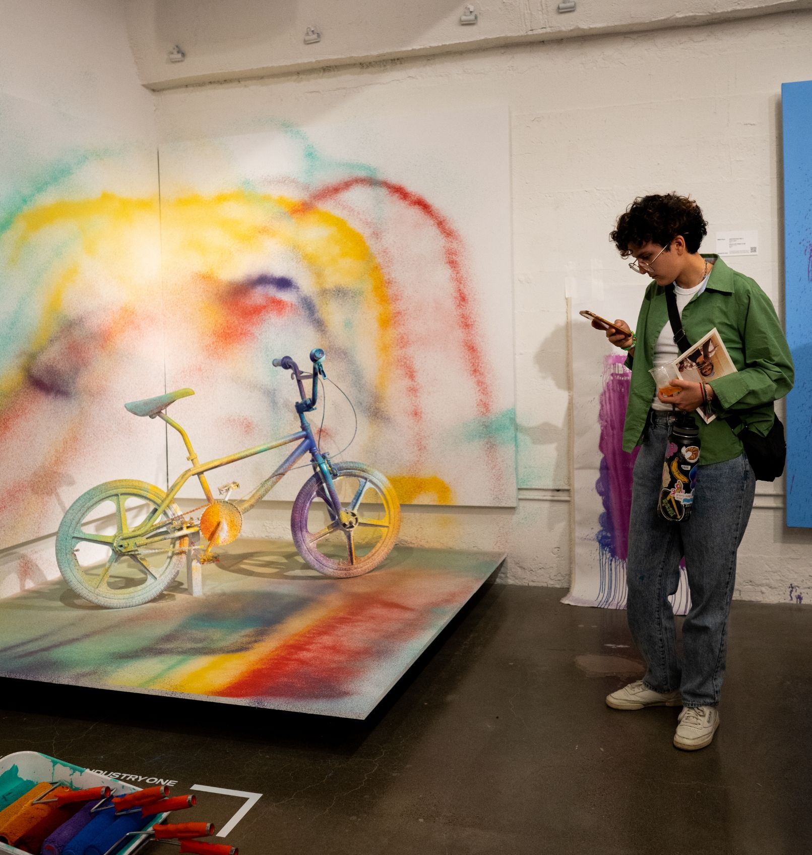 Person next to painted bmx bike exhibit looking at their phone