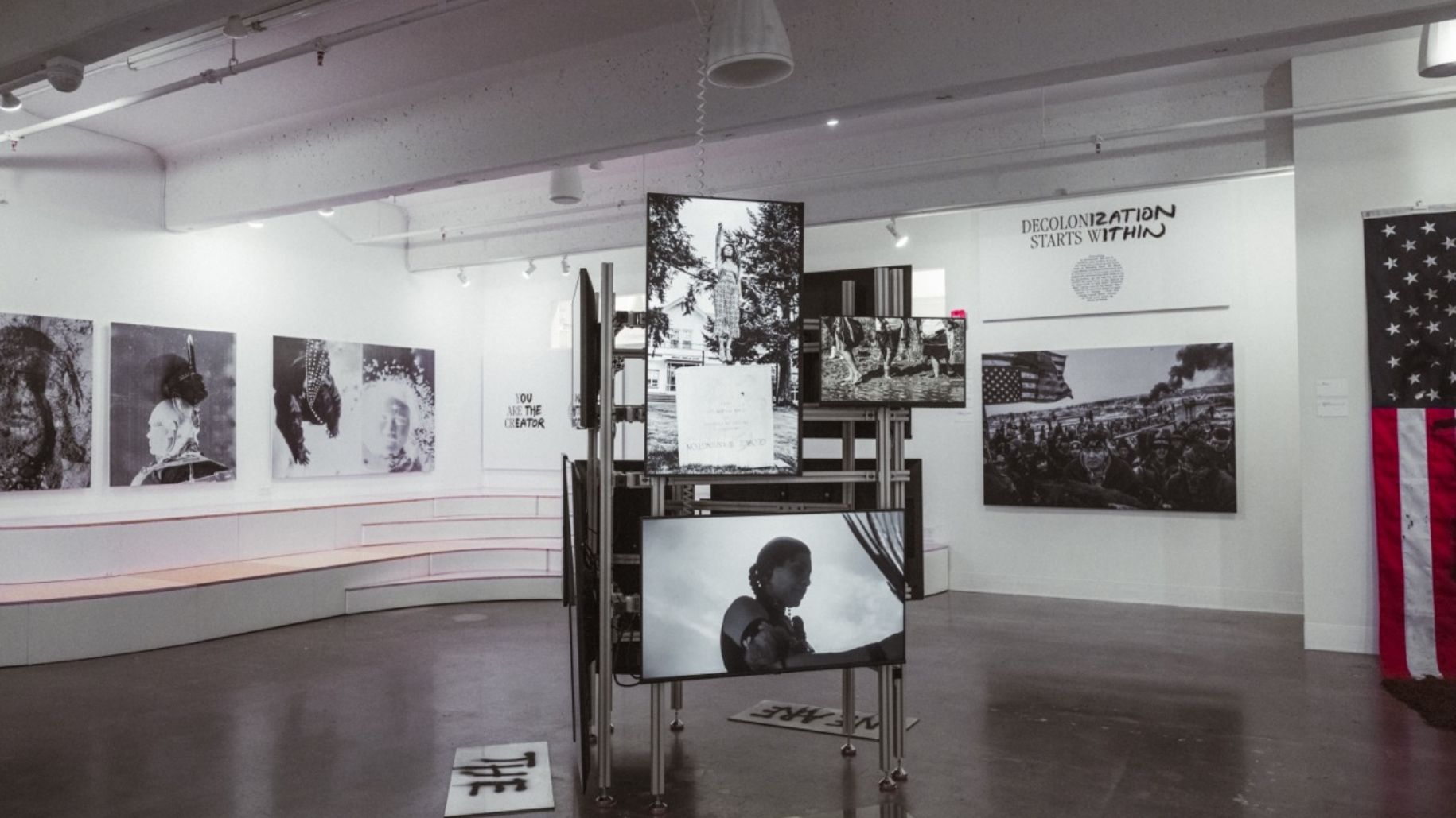 Video installation in middle of gallery surrounded by photos