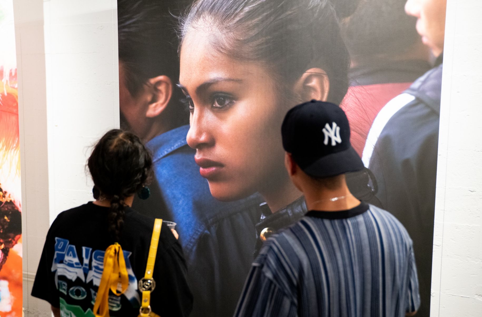 back of two people looking at a large print of woman's face in profile